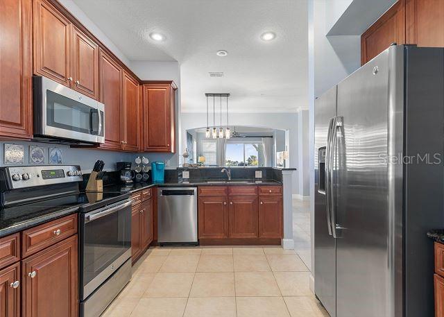200 Cinnamon Beach Way Unit 131, Palm Coast, FL 32137 - kitchen featuring appliances with stainless steel finishes, light tile patterned floors, recessed lighting, brown cabinetry, and a chandelier