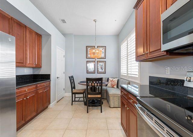 200 Cinnamon Beach Way Unit 131, Palm Coast, FL 32137 - kitchen featuring stainless steel appliances, a chandelier, light tile patterned floors, dark stone countertops, and hanging light fixtures