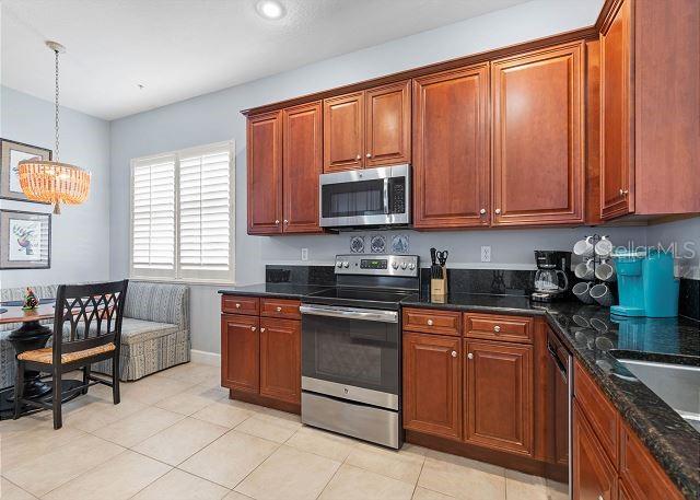 200 Cinnamon Beach Way Unit 131, Palm Coast, FL 32137 - kitchen with appliances with stainless steel finishes, a chandelier, light tile patterned flooring, pendant lighting, and dark stone countertops