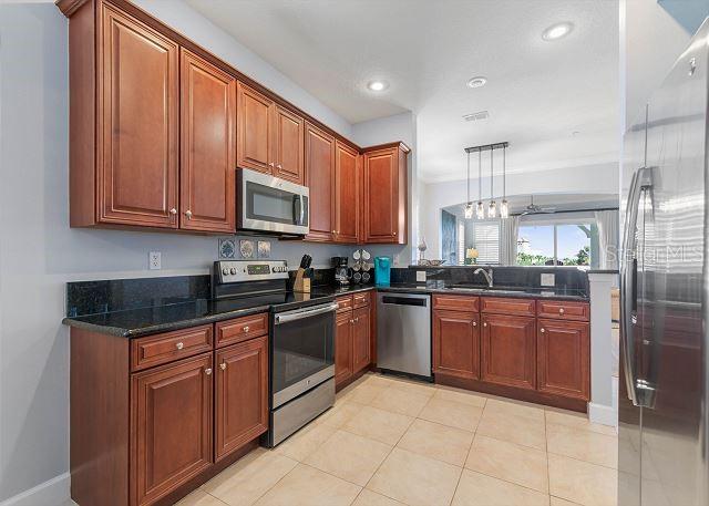 200 Cinnamon Beach Way Unit 131, Palm Coast, FL 32137 - kitchen with stainless steel appliances, dark stone counters, brown cabinets, pendant lighting, and recessed lighting