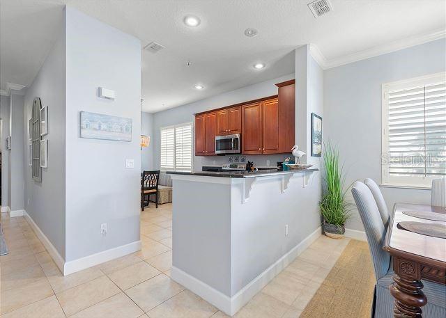 200 Cinnamon Beach Way Unit 131, Palm Coast, FL 32137 - kitchen with stainless steel microwave, a peninsula, a breakfast bar, recessed lighting, and light tile patterned floors