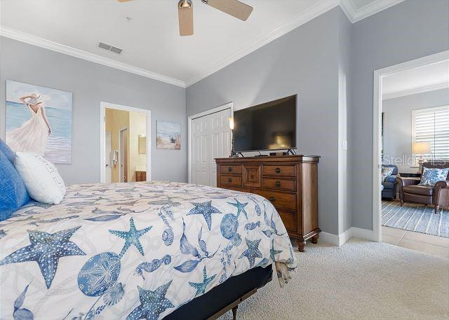 200 Cinnamon Beach Way Unit 131, Palm Coast, FL 32137 - bedroom with ornamental molding, carpet floors, ensuite bathroom, a closet, and ceiling fan