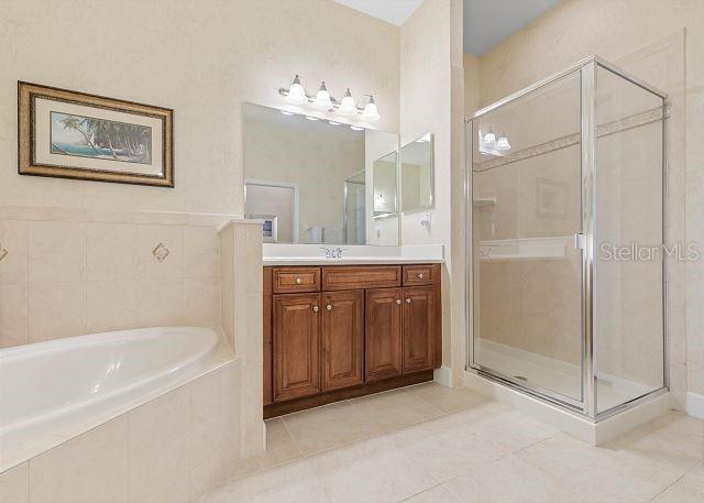 200 Cinnamon Beach Way Unit 131, Palm Coast, FL 32137 - full bathroom featuring tile patterned floors, vanity, a bath, and a shower stall