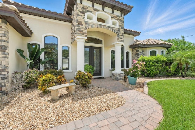 42 Felwood Ln, Palm Coast, FL 32137 - property entrance with stucco siding, a tiled roof, french doors, and stone siding