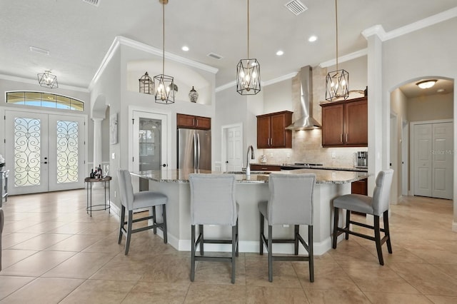 42 Felwood Ln, Palm Coast, FL 32137 - kitchen with wall chimney range hood, freestanding refrigerator, crown molding, arched walkways, and decorative backsplash