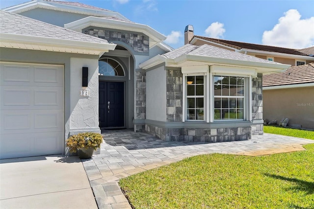 12 Comet Ct, Palm Coast, FL 32137 - property entrance with an attached garage, stone siding, a lawn, and stucco siding