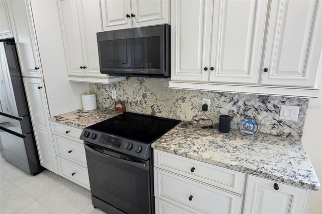 12 Comet Ct, Palm Coast, FL 32137 - kitchen featuring black microwave, range with electric stovetop, fridge, decorative backsplash, and white cabinetry