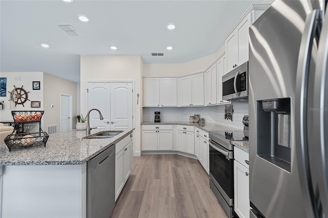 7 Pine Bush Ln, Palm Coast, FL 32164 - kitchen featuring appliances with stainless steel finishes, light wood-type flooring, white cabinetry, decorative backsplash, and recessed lighting