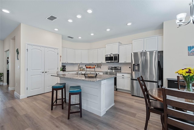 7 Pine Bush Ln, Palm Coast, FL 32164 - kitchen with stainless steel appliances, light wood finished floors, tasteful backsplash, a center island with sink, and recessed lighting