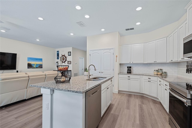 7 Pine Bush Ln, Palm Coast, FL 32164 - kitchen featuring stainless steel appliances, light wood-style flooring, white cabinetry, light stone counters, and open floor plan