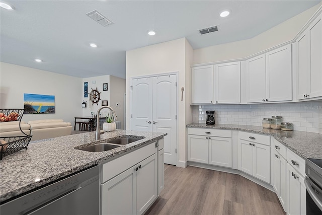 7 Pine Bush Ln, Palm Coast, FL 32164 - kitchen with dishwasher, white cabinets, light wood-type flooring, tasteful backsplash, and light stone counters