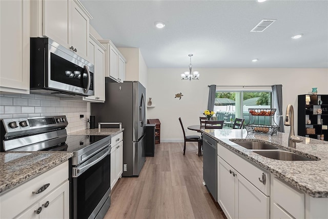 7 Pine Bush Ln, Palm Coast, FL 32164 - kitchen featuring appliances with stainless steel finishes, tasteful backsplash, a chandelier, light wood-type flooring, and white cabinets