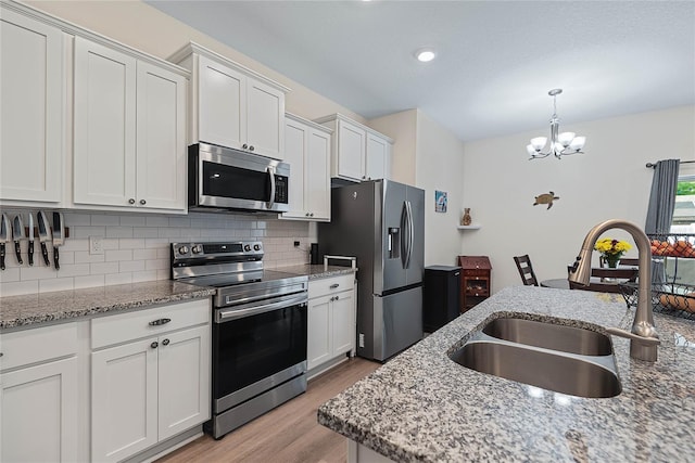 7 Pine Bush Ln, Palm Coast, FL 32164 - kitchen with appliances with stainless steel finishes, light wood finished floors, backsplash, white cabinetry, and a chandelier
