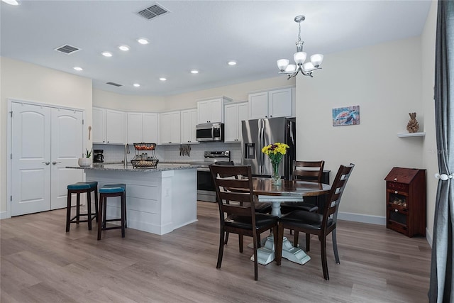 7 Pine Bush Ln, Palm Coast, FL 32164 - kitchen with appliances with stainless steel finishes, tasteful backsplash, a chandelier, a kitchen island with sink, and white cabinets