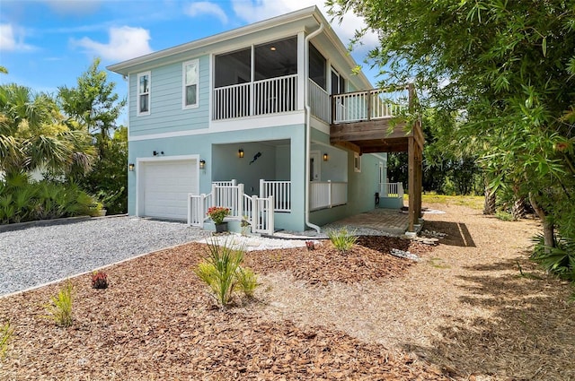 19 Bay Dr, Palm Coast, FL 32137 - view of front of home with an attached garage, gravel driveway, a sunroom, and stucco siding