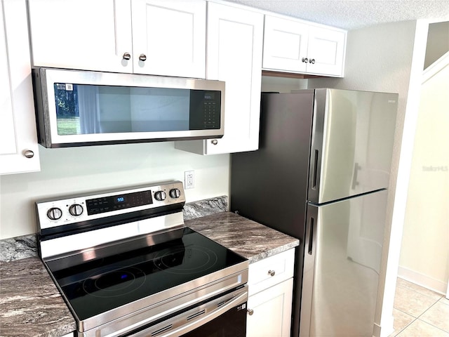 3628 S Central Ave Unit 5, Flagler Beach, FL 32136 - kitchen with appliances with stainless steel finishes, white cabinets, light tile patterned floors, a textured ceiling, and dark countertops