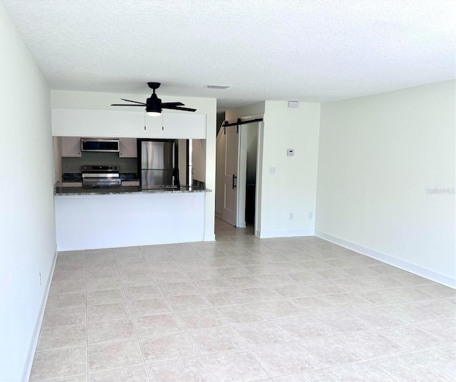 3628 S Central Ave Unit 5, Flagler Beach, FL 32136 - unfurnished living room featuring a textured ceiling, a barn door, a ceiling fan, and light tile patterned floors