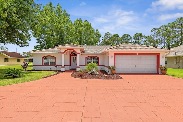 54 Pine Grove Dr, Palm Coast, FL 32164 - mediterranean / spanish-style home featuring a tiled roof, decorative driveway, stucco siding, a front lawn, and a garage
