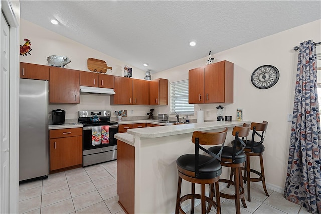 54 Pine Grove Dr, Palm Coast, FL 32164 - kitchen with appliances with stainless steel finishes, a peninsula, under cabinet range hood, light countertops, and light tile patterned floors