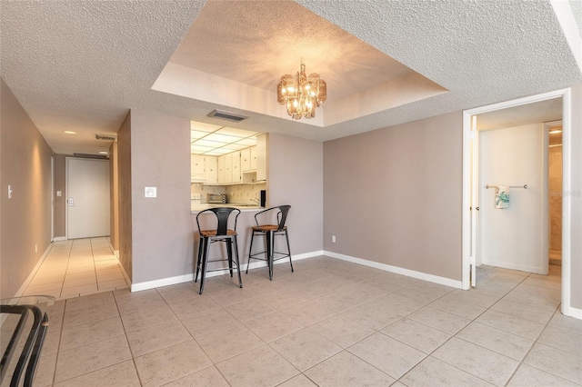 3047 S Atlantic Ave Unit 706, Daytona Beach, FL 32118 - dining area featuring a textured ceiling, light tile patterned flooring, a chandelier, and a raised ceiling
