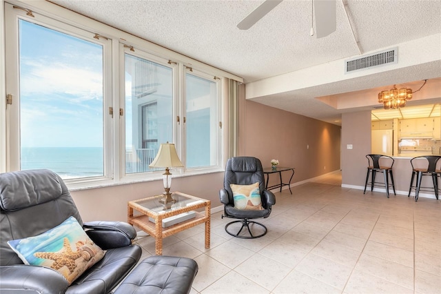 3047 S Atlantic Ave Unit 706, Daytona Beach, FL 32118 - living area featuring a ceiling fan, light tile patterned floors, a textured ceiling, and a chandelier