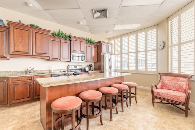 3047 S Atlantic Ave Unit 706, Daytona Beach, FL 32118 - kitchen with stainless steel appliances, a paneled ceiling, a breakfast bar area, a center island, and healthy amount of natural light