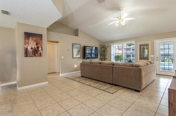4 Essington Ln, Palm Coast, FL 32164 - living area with light tile patterned floors, a ceiling fan, and vaulted ceiling