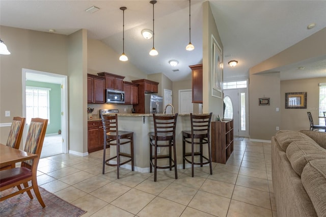 4 Essington Ln, Palm Coast, FL 32164 - kitchen with stainless steel appliances, vaulted ceiling, open floor plan, a peninsula, and light tile patterned floors