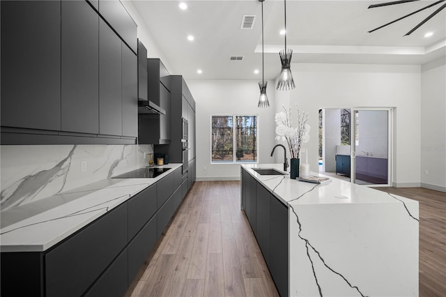 179 Eric Dr, Palm Coast, FL 32164 - kitchen featuring modern cabinets, dark cabinets, recessed lighting, an island with sink, and light wood-style flooring