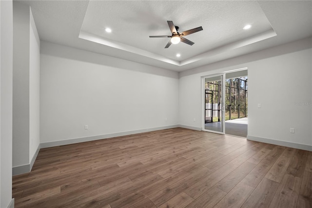 179 Eric Dr, Palm Coast, FL 32164 - empty room with a raised ceiling, ceiling fan, wood finished floors, recessed lighting, and a textured ceiling
