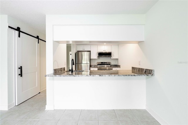 3630 S Central Ave, Flagler Beach, FL 32136 - kitchen featuring stainless steel appliances, a barn door, stone counters, and a peninsula