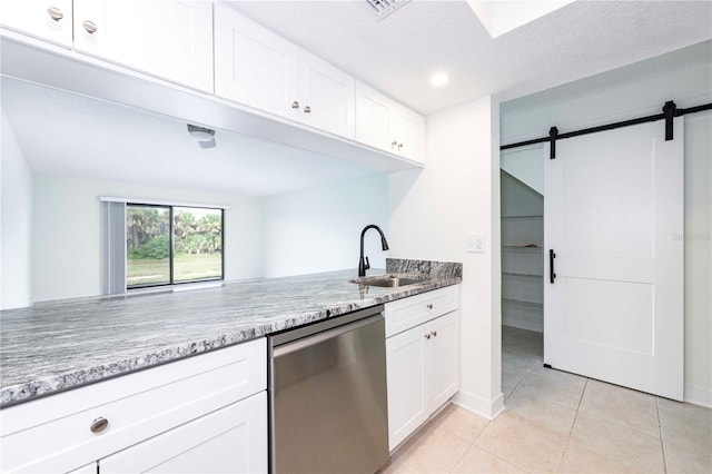 3630 S Central Ave, Flagler Beach, FL 32136 - kitchen featuring dishwasher, a barn door, light tile patterned floors, white cabinets, and light stone counters