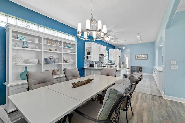 101 N 22nd St, Flagler Beach, FL 32136 - dining space with a chandelier, light wood-style flooring, arched walkways, and rail lighting