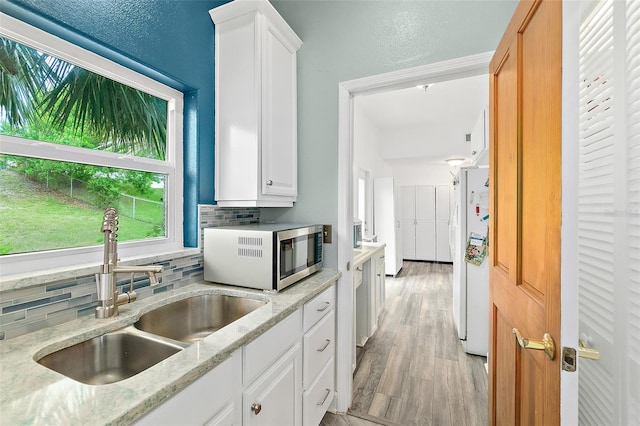 101 N 22nd St, Flagler Beach, FL 32136 - kitchen with stainless steel microwave, tasteful backsplash, white cabinets, and light stone countertops