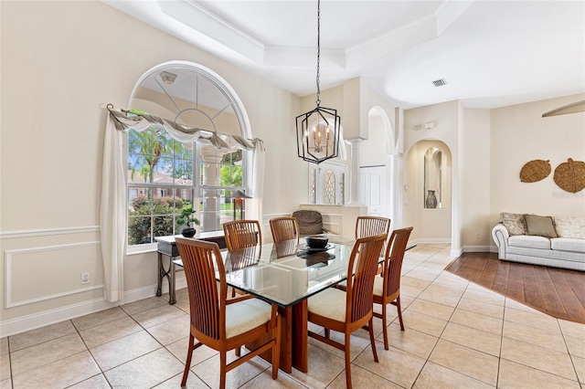 68 Egret Trl, Palm Coast, FL 32164 - dining room with light tile patterned flooring, a chandelier, crown molding, a tray ceiling, and arched walkways