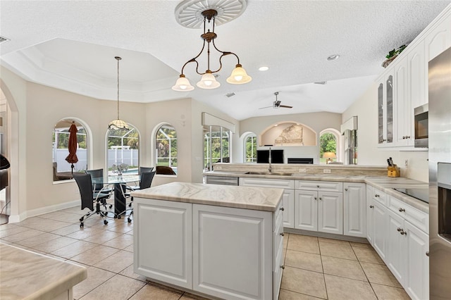 68 Egret Trl, Palm Coast, FL 32164 - kitchen featuring light tile patterned floors, a ceiling fan, a peninsula, glass insert cabinets, and a textured ceiling