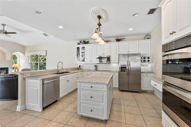 68 Egret Trl, Palm Coast, FL 32164 - kitchen with appliances with stainless steel finishes, a peninsula, light countertops, glass insert cabinets, and white cabinetry
