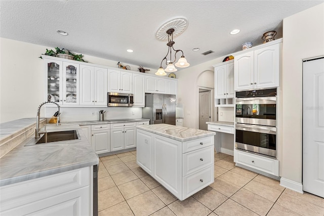 68 Egret Trl, Palm Coast, FL 32164 - kitchen with stainless steel appliances, hanging light fixtures, white cabinets, light tile patterned floors, and glass insert cabinets