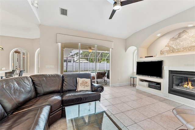 68 Egret Trl, Palm Coast, FL 32164 - living area featuring a ceiling fan, tile patterned flooring, arched walkways, and a glass covered fireplace