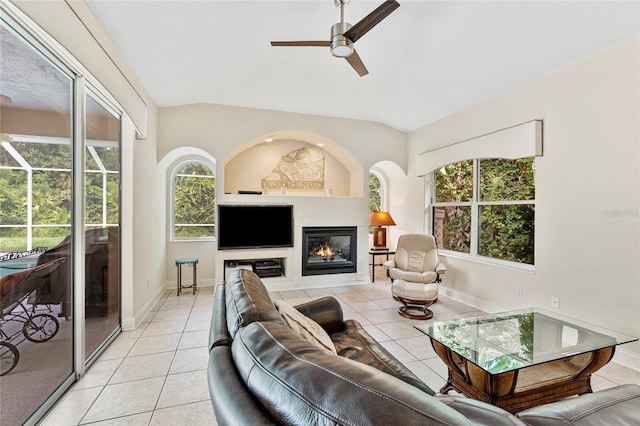 68 Egret Trl, Palm Coast, FL 32164 - living room featuring ceiling fan, vaulted ceiling, plenty of natural light, light tile patterned flooring, and a glass covered fireplace