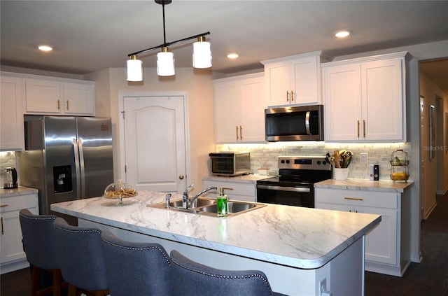 35 Putter Dr, Palm Coast, FL 32164 - kitchen with appliances with stainless steel finishes, white cabinets, decorative backsplash, a center island with sink, and hanging light fixtures