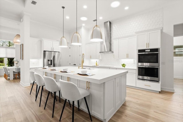 476 Stirling Bridge Dr, Ormond Beach, FL 32174 - kitchen featuring stainless steel appliances, wall chimney exhaust hood, a kitchen island with sink, light countertops, and backsplash