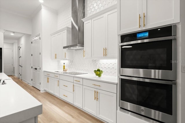 476 Stirling Bridge Dr, Ormond Beach, FL 32174 - kitchen with double oven, wall chimney range hood, light wood-type flooring, tasteful backsplash, and black electric cooktop