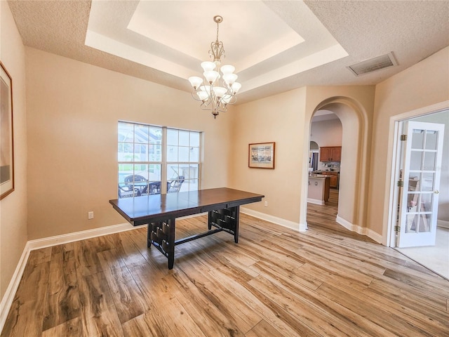 8 Wiltshire Pl, Palm Coast, FL 32164 - dining room with arched walkways, light wood finished floors, a raised ceiling, and a chandelier