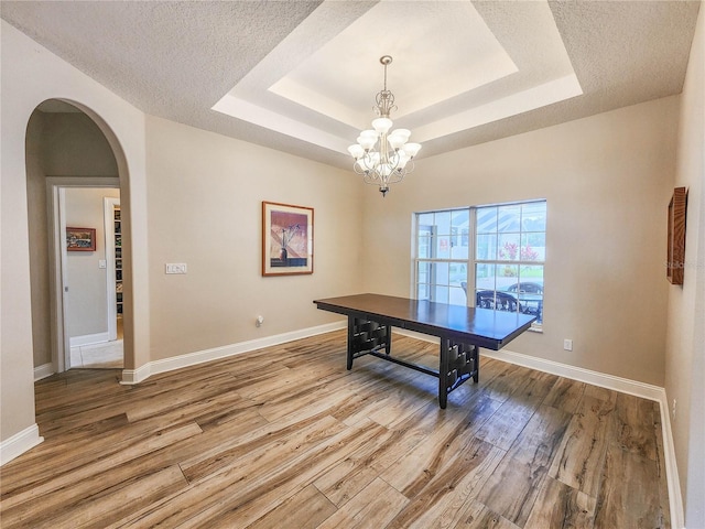 8 Wiltshire Pl, Palm Coast, FL 32164 - dining room with wood finished floors, a chandelier, a raised ceiling, and arched walkways