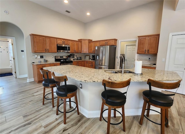 8 Wiltshire Pl, Palm Coast, FL 32164 - kitchen with stainless steel appliances, a high ceiling, decorative backsplash, a breakfast bar area, and light wood-style floors