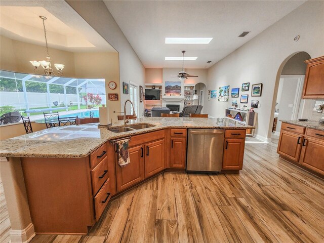 8 Wiltshire Pl, Palm Coast, FL 32164 - kitchen with stainless steel dishwasher, light wood-type flooring, a fireplace, open floor plan, and arched walkways
