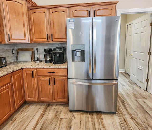 8 Wiltshire Pl, Palm Coast, FL 32164 - kitchen with stainless steel fridge with ice dispenser, light wood finished floors, light stone countertops, backsplash, and brown cabinets