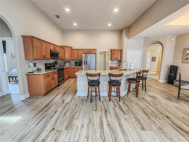 8 Wiltshire Pl, Palm Coast, FL 32164 - kitchen with appliances with stainless steel finishes, arched walkways, a high ceiling, backsplash, and a breakfast bar