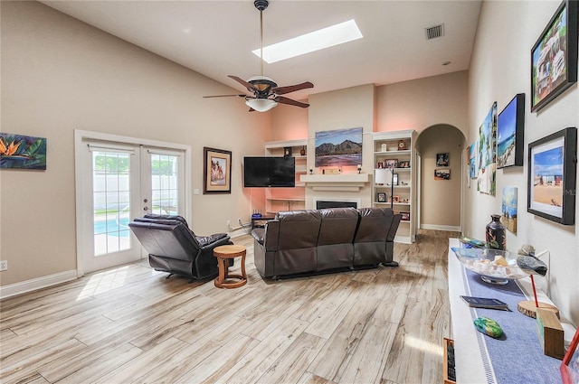 8 Wiltshire Pl, Palm Coast, FL 32164 - living area featuring light wood-type flooring, a towering ceiling, a fireplace, french doors, and arched walkways